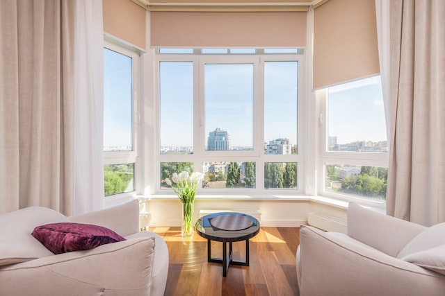 General shot of a white living room with tall windows looking out onto a city